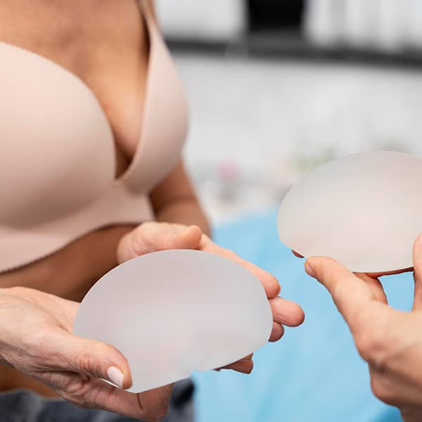 Plastic surgeon showing woman breast implants before procedure.